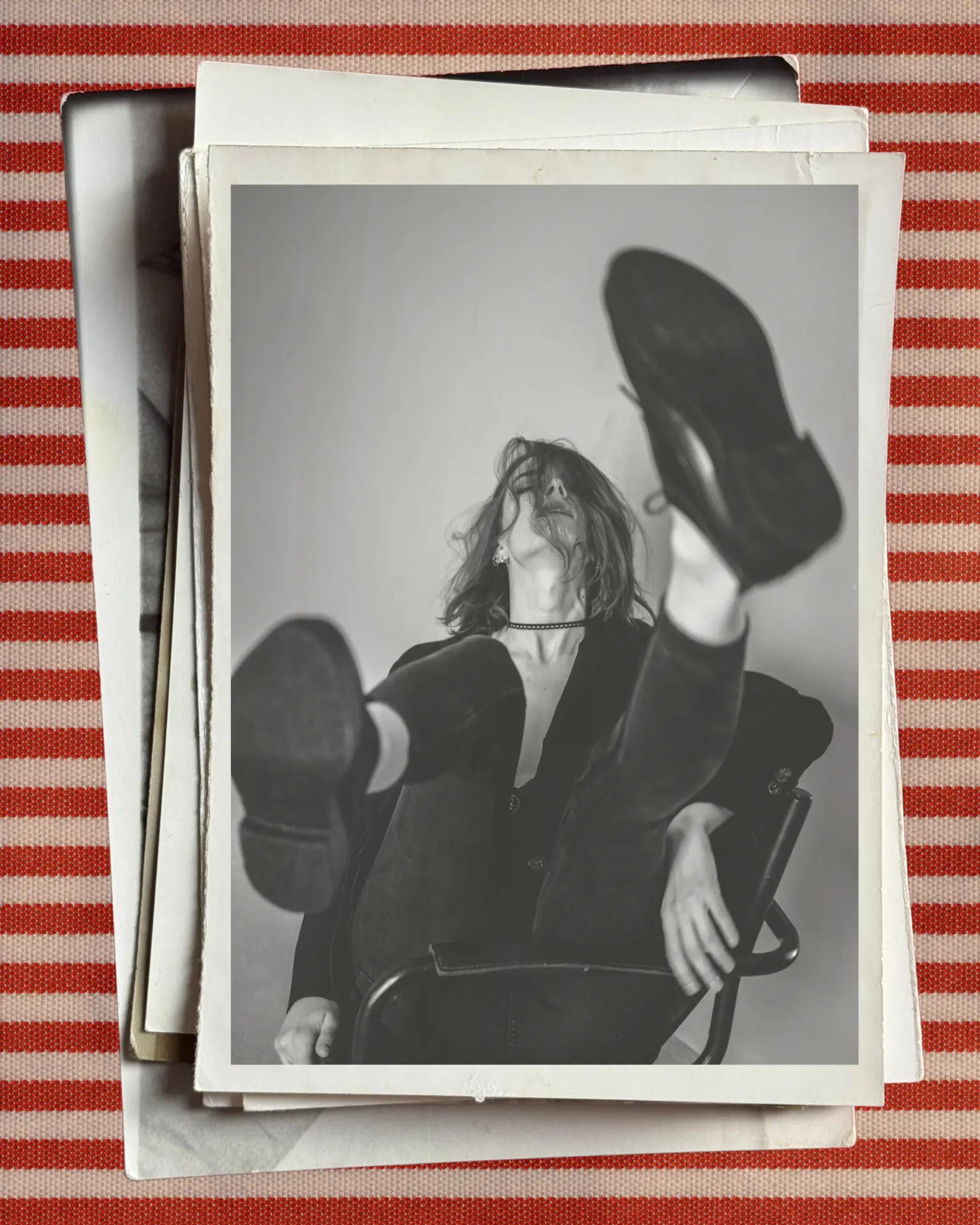 Woman kicking her legs up in a chair, striped backdrop